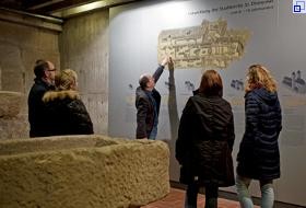 Im Museum St. Dionys - Mittelalterliche Ausgrabungen: Auf einem großen Grundriss an der Wand erklärt ein Mann Teilnehmerinnen und Teilnehmern einer Führung die Baugeschichte der Kirche.