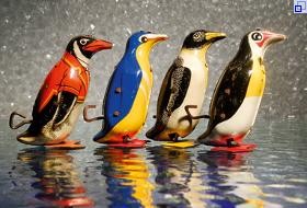 Ausstellungsfotografie: Blechspielzeug: Vier Pinguine marschieren hintereinander, die Schlüssel zum Aufziehen sind gut sichtbar