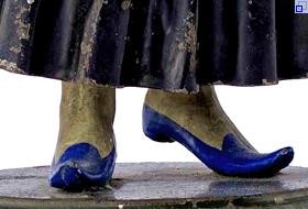 Detail: Füße in leuchtend blauen Schuhen unter einem langen Faltenrock.