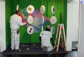 Zwei Maler streichen mit Pinsel und Farbrolle Elemente für die neue Ausstellung.