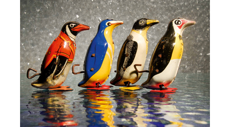 Ausstellungsfotografie: Blechspielzeug: Vier Pinguine marschieren hintereinander, die Schlüssel zum Aufziehen sind gut sichtbar
