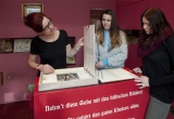 Ausstellungsraum im J. F. Schreiber-Museum mit drei Besucherinnen, die interessiert Zeichnungen betrachten.